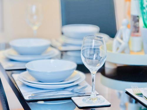a table with plates and a wine glass on it at Elegant 1 bed flat, Sleeps 4, Free parking, Pet friendly, Pudsey, Leeds in Pudsey