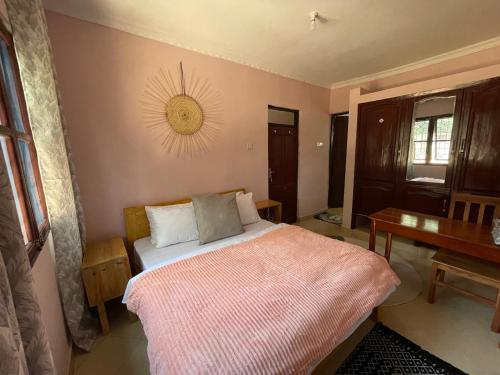 a bedroom with a bed with a pink blanket on it at Serene homes in Mwanza