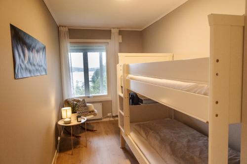 a bedroom with bunk beds and a chair and a window at Apartment with exceptional view in Ålesund