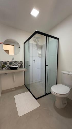 a bathroom with a glass shower and a toilet at Chalé Sol Nascente Milagres in São Miguel dos Milagres