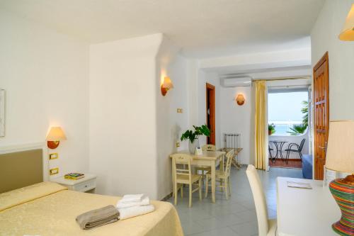 a room with a bed and a dining room at Hotel Grazia alla Scannella in Ischia