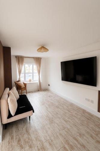 a living room with a couch and a flat screen tv at 3BR Detached Home, Driveway & Large Rear Garden in Hogganfield