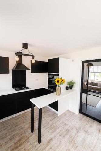 a kitchen with a white table and black cabinets at 3BR Detached Home, Driveway & Large Rear Garden in Hogganfield
