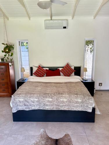 a bedroom with a large bed with red pillows at Bird Song Bedroom in Cape Town