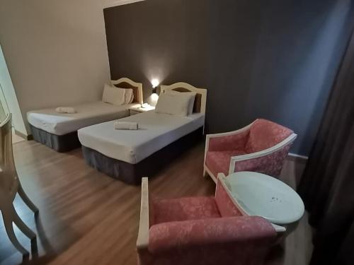a hotel room with two beds and a chair at Hotel Seri Malaysia Kulim in Kulim