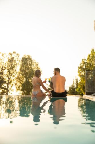 a man and woman sitting on the edge of a swimming pool at Mazarine Hotel, Vlorë, Albania in Vlorë