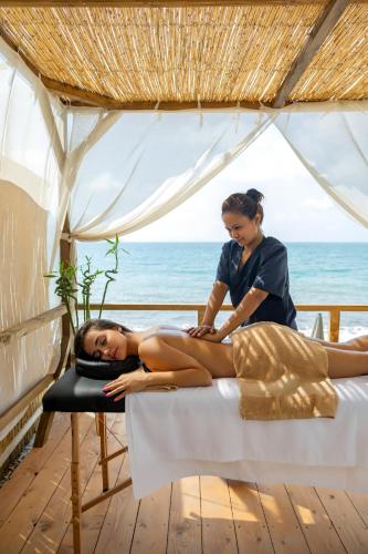 a woman laying on a bed next to a woman getting a massage at Mazarine Hotel, Vlorë, Albania in Vlorë