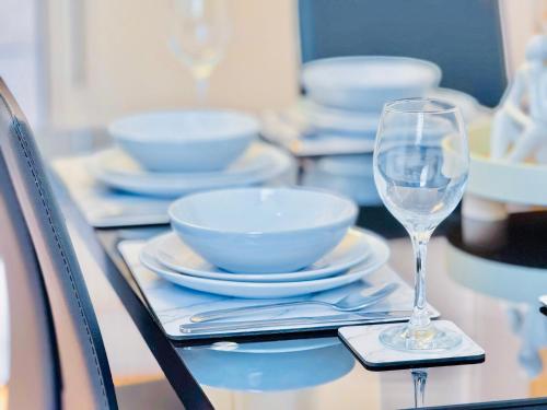 a table with plates and a wine glass on it at Elegant 1 bed flat, Sleeps 4, Free parking, Pet friendly, Pudsey, Leeds in Pudsey