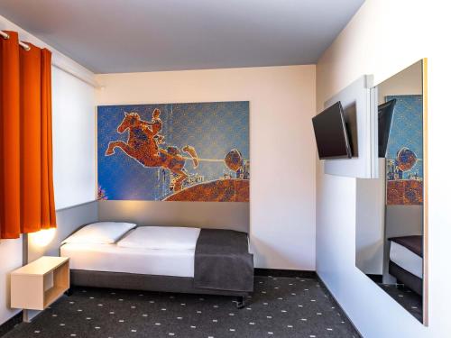 a bedroom with a bed and a painting on the wall at B&B HOTEL Magdeburg-City in Magdeburg