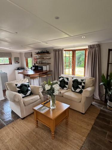 a living room with two couches and a table at Devonshire Cottage in Nottingham Road