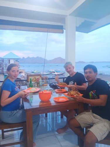 a group of people sitting at a table eating food at Jojo Komodo Homestay in Komodo