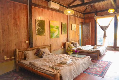a bedroom with two beds in a room with wooden walls at Dó homestay in Sa Pa