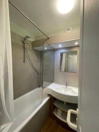 a bathroom with a sink and a tub and a mirror at Newly renovated flat on the slopes in Avoriaz
