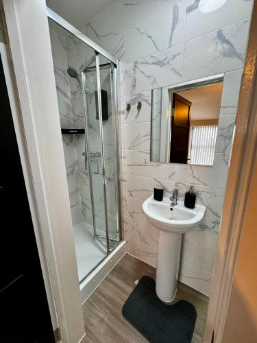 a white bathroom with a sink and a shower at Stylish and Bright 1 Bedroom Flat in Wallasey