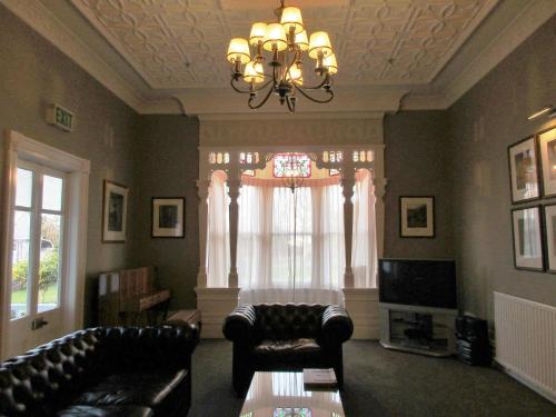 a living room with a couch and a chandelier at Valmai House & Motel Cambridge in Cambridge