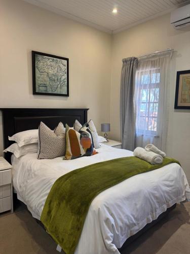 a bedroom with a large bed with a green blanket at Rivonia Garden Suites in Johannesburg