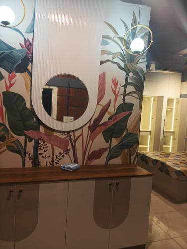 a bathroom with a mirror and a wall with flowers at Rustic Roots Inn in Bangalore