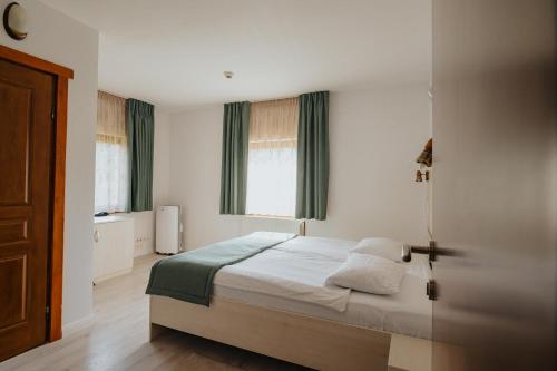 a bedroom with a bed and two windows at Juliu's Panzio Csikszereda in Miercurea-Ciuc
