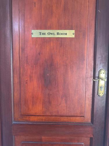 a wooden door with a sign that reads the owl room at Rivonia Garden Suites in Johannesburg