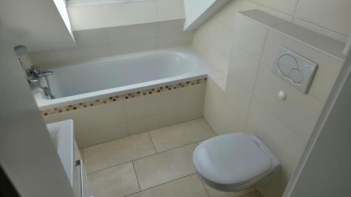 a white bathroom with a toilet and a bath tub at Privatzimmer Freimann in Munich