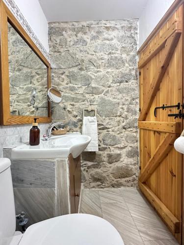 a bathroom with a sink and a stone wall at Eria Moutoullas House in Moutoullas
