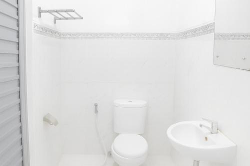 Un baño blanco con inodoro y lavabo. en Hotel Griya Kopi, en Pekalongan