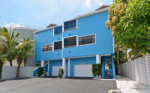 a blue house with a fence and palm trees at Happy Blue Coconuts - South in Siesta Key
