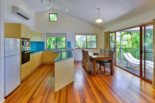 
a kitchen with a table, chairs and a refrigerator at Heliconia Grove 9 in Hamilton Island
