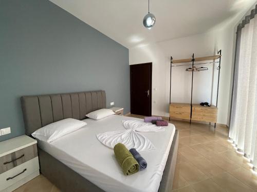 a bedroom with a large white bed with towels on it at Skapeta Apartments in Sarandë