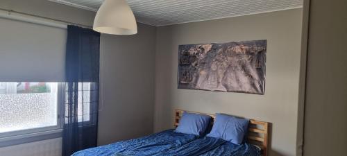 ein Schlafzimmer mit einem Bett und einem Gemälde an der Wand in der Unterkunft Sackleninkatu in Pori