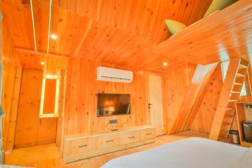 a room with a bed and a tv and a staircase at Dreamation Resorts in Bīr