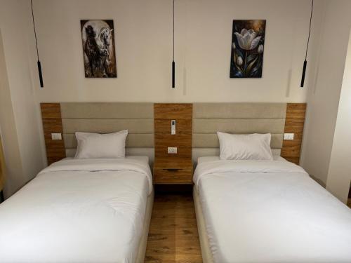two beds in a room with paintings on the wall at Palacio Pyramids Hotel in Cairo