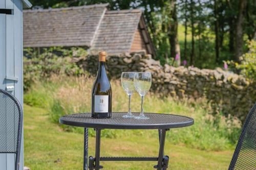 a bottle of wine and two glasses on a table at Percy Shepherd's Hut - High Borrans Farm in Ings