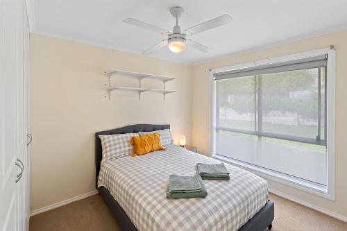 Un dormitorio con una cama con ventilador de techo y una ventana. en Comfortable 4-Bedroom Home with Backyard Escape, en Mount Gambier