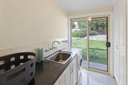 cocina con fregadero y ventana grande en Comfortable 4-Bedroom Home with Backyard Escape, en Mount Gambier
