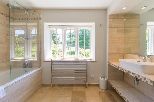 a bathroom with a tub and a sink and a window at The Dairy House in Ilminster