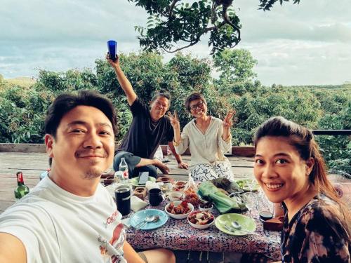 a group of people sitting around a table with food at Napahong Treehouse นาป่าฮง Andromeda & Cassiopeia in Ban Pa Ha