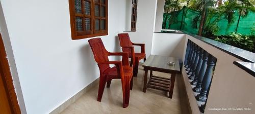 two chairs and a table in a room with an aquarium at Abba's Glory Land - Agonda in Agonda