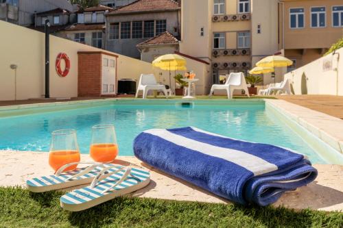 two glasses of orange juice and towels next to a swimming pool at 731 Costa Cabral Metro Residence in Porto