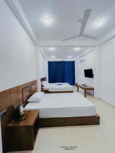 a bedroom with a large bed and a tv at Ocean Light Mirissa in Mirissa