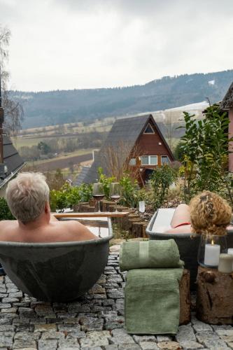 a man sitting in a bath tub on a patio at Alva Rhön Panorama Ferienhaus - Auszeit mit Kamin in Frankenheim