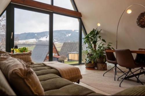 a living room with a couch and a large window at Alva Rhön Panorama Ferienhaus - Auszeit mit Kamin in Frankenheim