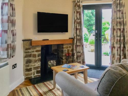 a living room with a fireplace with a flat screen tv at The Bothy in Bradworthy