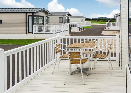 a wooden deck with a table and chairs on it at Riverside Holiday Village in Uphill
