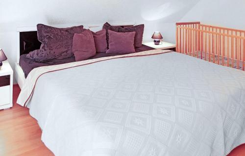 a bedroom with a large white bed with purple pillows at Ferienhaus Verchen in Verchen