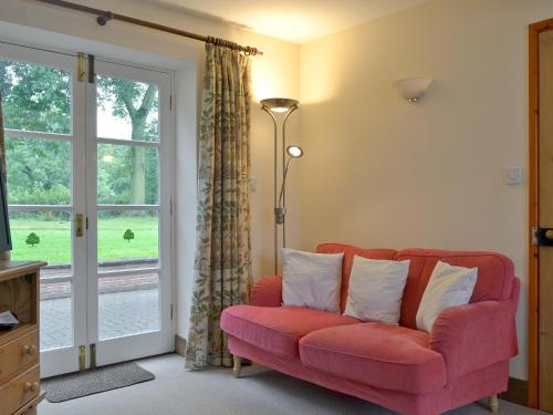 a living room with a red couch and a window at Garden Farm Cottage in Ilam