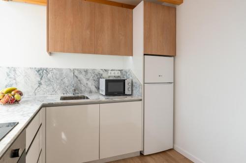 a kitchen with white cabinets and a microwave at Authentic Studio with Terrace by HostWise in Porto