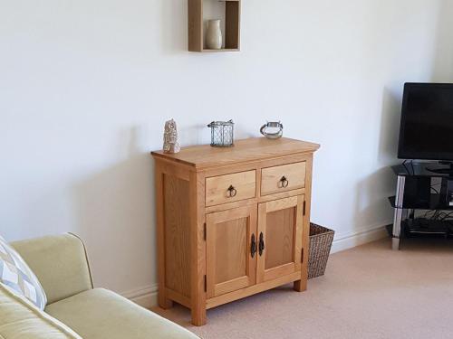 a wooden cabinet in a living room with a tv at Meadowside Apartment in Fowey