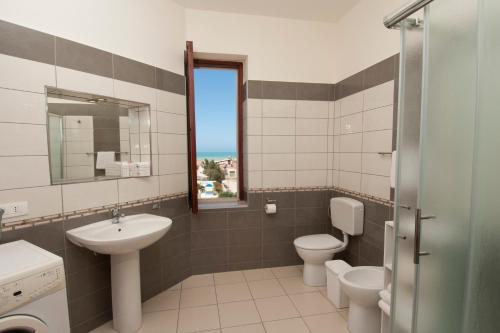 y baño con 2 aseos, lavamanos y espejo. en Residence Sicilia Mare- casa vacanza Scoglitti en Scoglitti