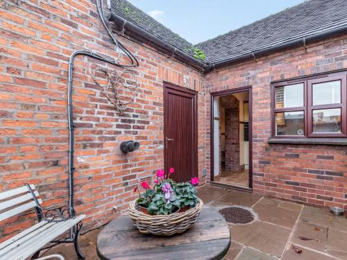 a brick building with a bench and a basket of flowers at The Stables - Uk30946 in Barthomley